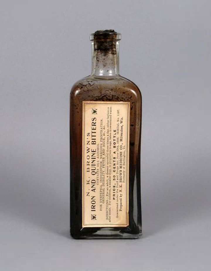Foto de frasco de vidro com tônico de ferro e quinina, um líquido espesso e marrom. No rótulo, há o texto: “N. K. Brown’s. Iron and quinine bitters”.