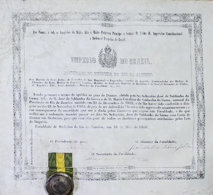 Digitalização do diploma da Faculdade de Medicina do Império do Brasil de 1869. No canto inferior esquerdo, há uma faixa nas cores verde e amarela e um selo.
