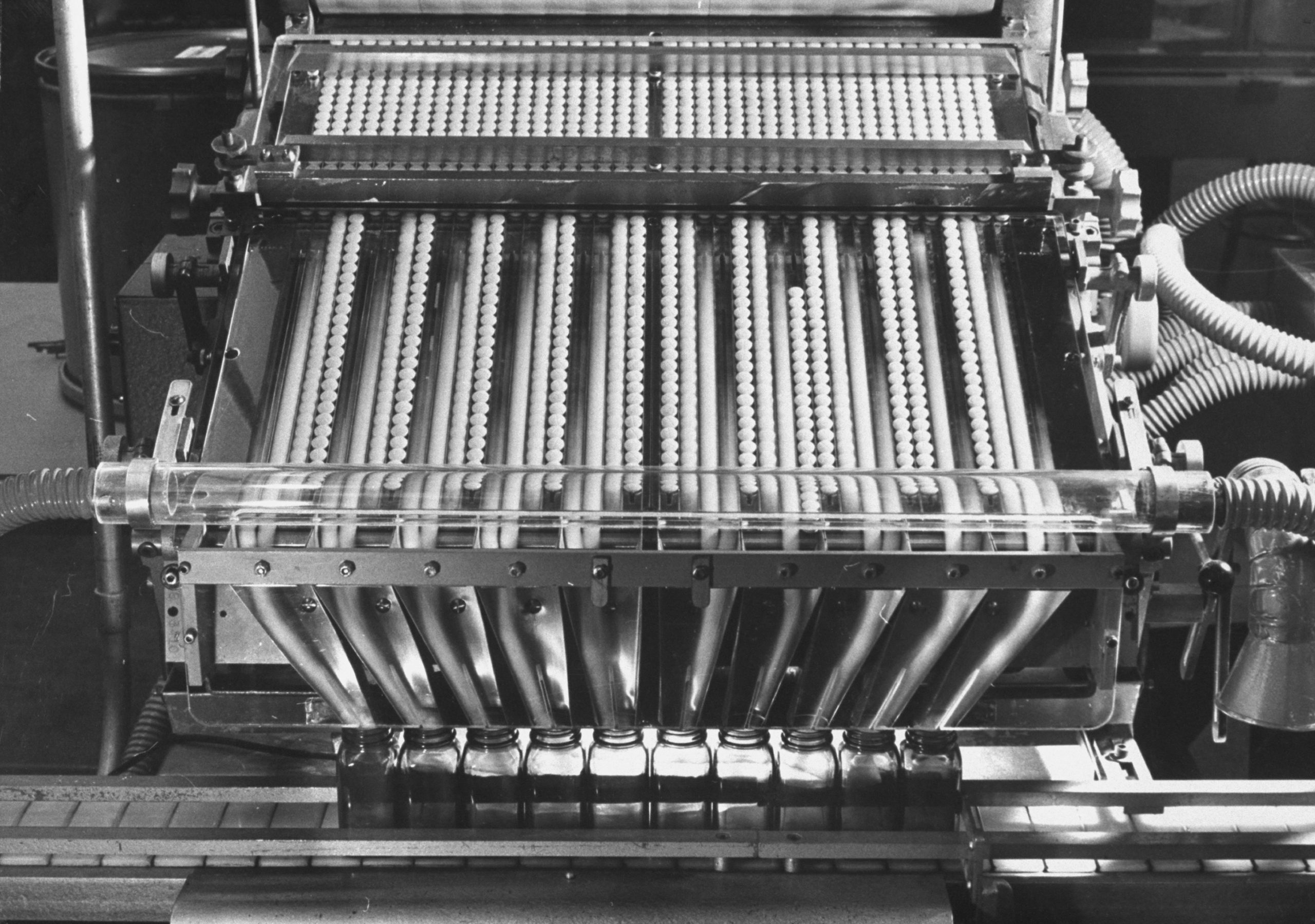 Foto em preto e branco de uma máquina de produção de medicamentos dos anos 1960.