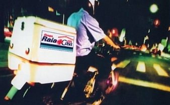 Foto de uma pessoa com capacete dirigindo uma moto de entrega de remédios da Droga Raia.